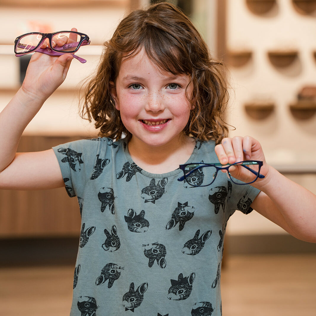 Little girl deciding between 2 pairs of glasses